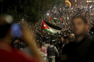 Jordanian protesters raise a national flag during a demonstration outside the prime minister’s office in the capital, Amman, on June 4. (Raad Adayleh/AP)